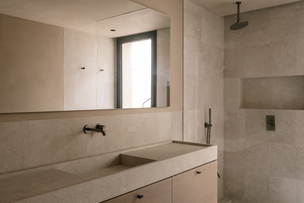 Badezimmer mit Steinwaschbecken und gebürsteten schwarzen Armaturen