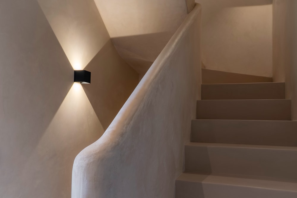 Die Treppe mit Kalkputz, beleuchtet von einer Wandleuchte, Fuster 8