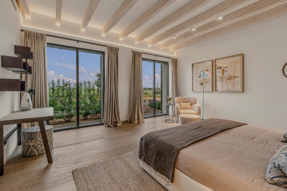 Ein Schlafzimmer mit Eichenboden und Balkendecke sowie verglasten Türen zum Garten, Santanyí III