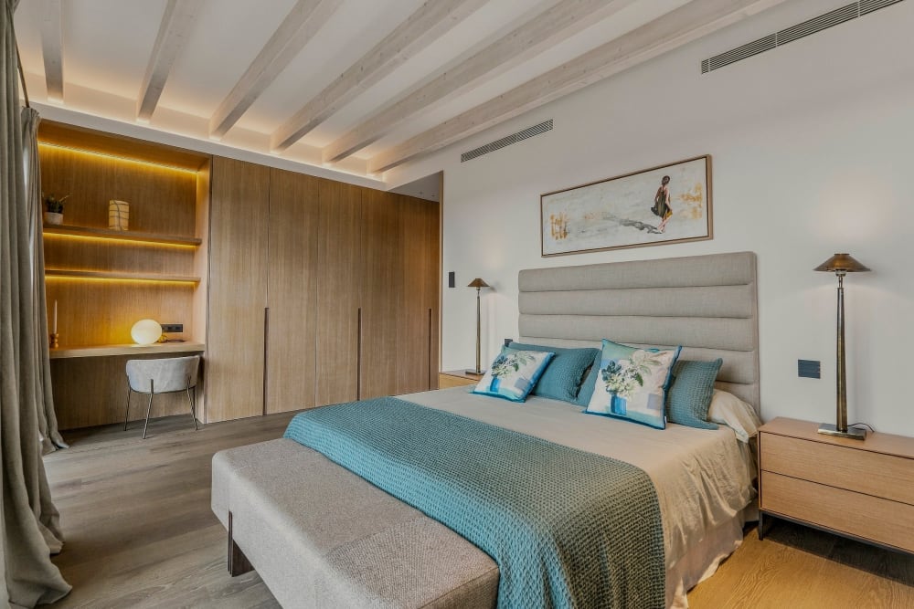 Ein Schlafzimmer mit blauer Tagesdecke, Eichenschränken und Balkendecke, Santanyí III