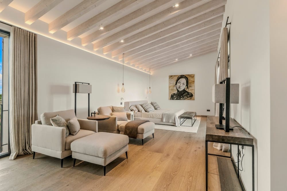 Das Wohnzimmer mit hellem Eichenboden, sichtbaren Holzbalken, einem Sofa und Sesseln, Santanyí III