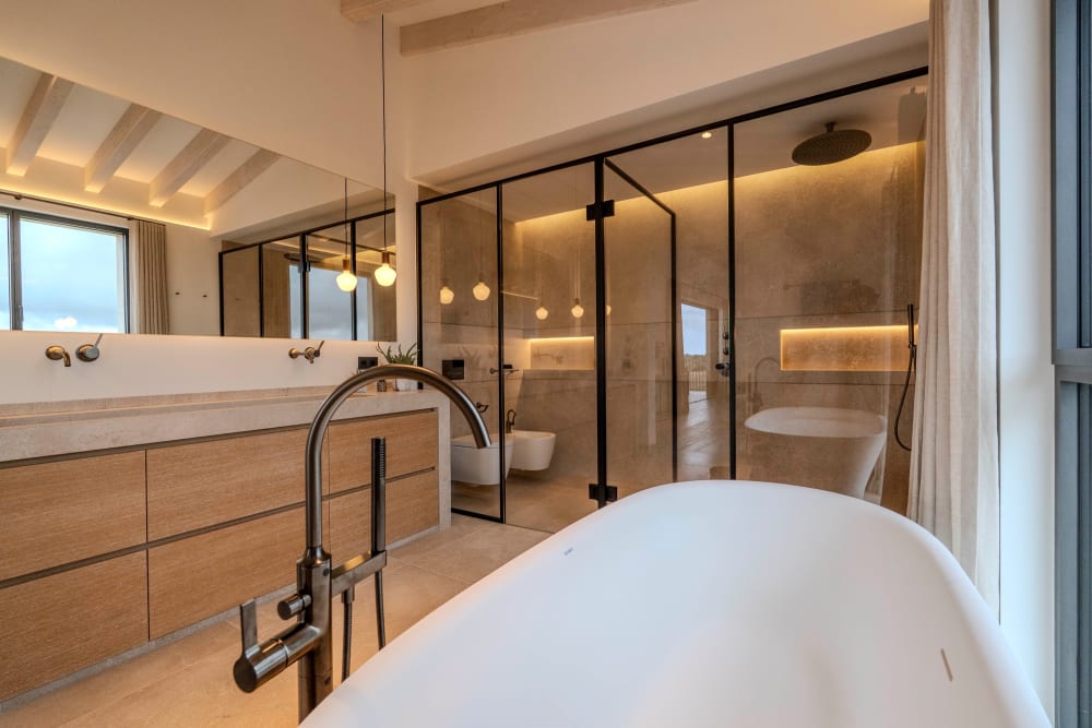 Die freistehende Badewanne und die Glasdusche im Badezimmer mit dem langen Waschtisch aus Eiche, Santanyí III