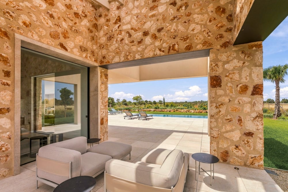 Eine überdachte Terrasse mit einem Sofa, die sich zum Pool und zum Rasen öffnet, Santanyí III