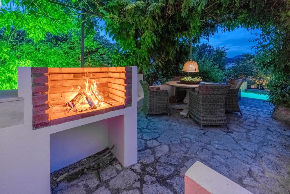 Der nachts beleuchtete Grill und der Tisch daneben, Exklusive Gartenwohnung
