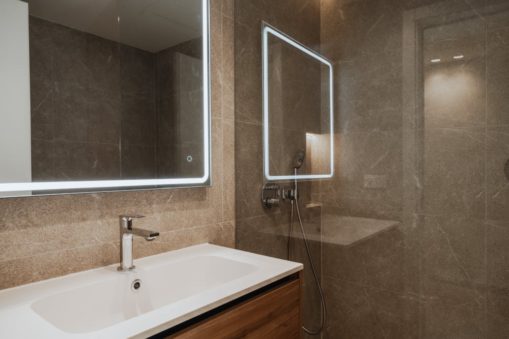 Ein Badezimmer, das Waschbecken und die Dusche aus braunem Stein, Reihenhaus in Portixol