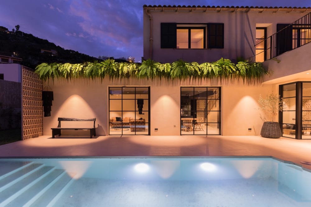 The same pool and terrace at night, with the rooms lit behind the glass, Falco 10