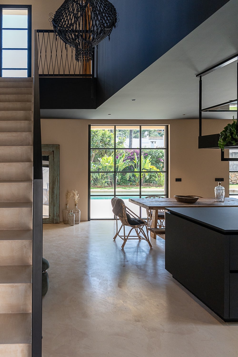 Kitchen and dining table seen from the stair, with the pool beyond the glass, Falco 10