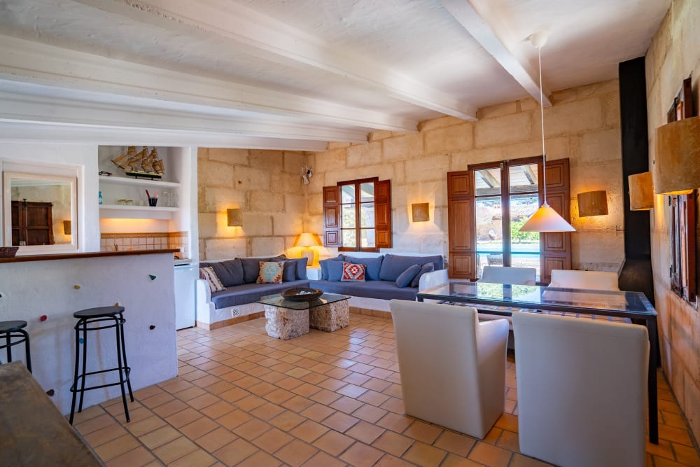 Guest-house living room in pale stone, with a sofa and a window, Hacienda Hermosa