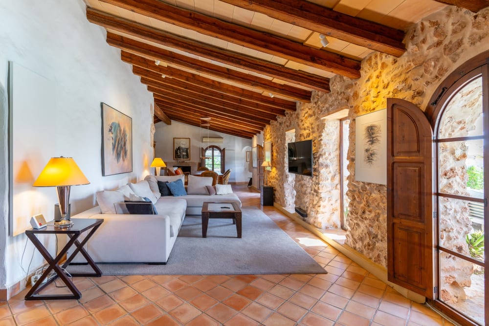 Living room under timber beams, with a stone wall and terracotta floors, Hacienda Hermosa