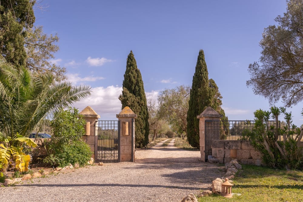 The entrance gate between stone pillars, with cypress along the track, Hacienda Hermosa