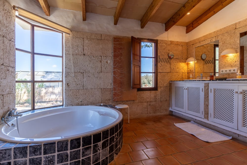Bathroom with a round bath, stone walls and two basins, Hacienda Hermosa