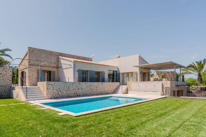 Das Haus aus Stein und Putz oberhalb des Pools und des Rasens, Finca Sant Llorenç
