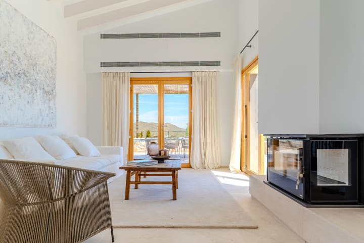 Der Wohnraum unter seiner Balkendecke, der Kamin und die Terrassentüren, Finca Sant Llorenç