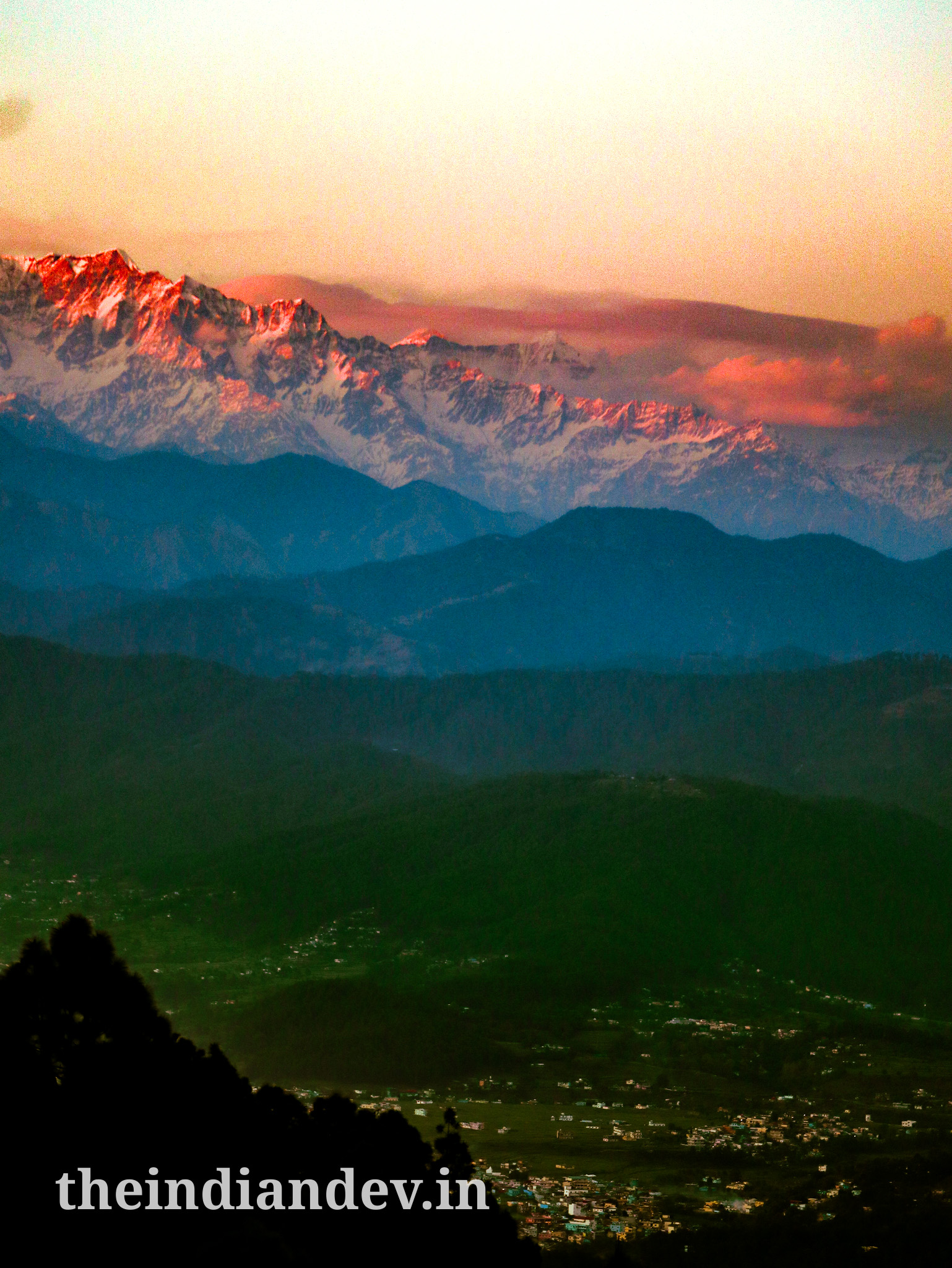 A picture of a village besides the ice capped mountains of Himalayas