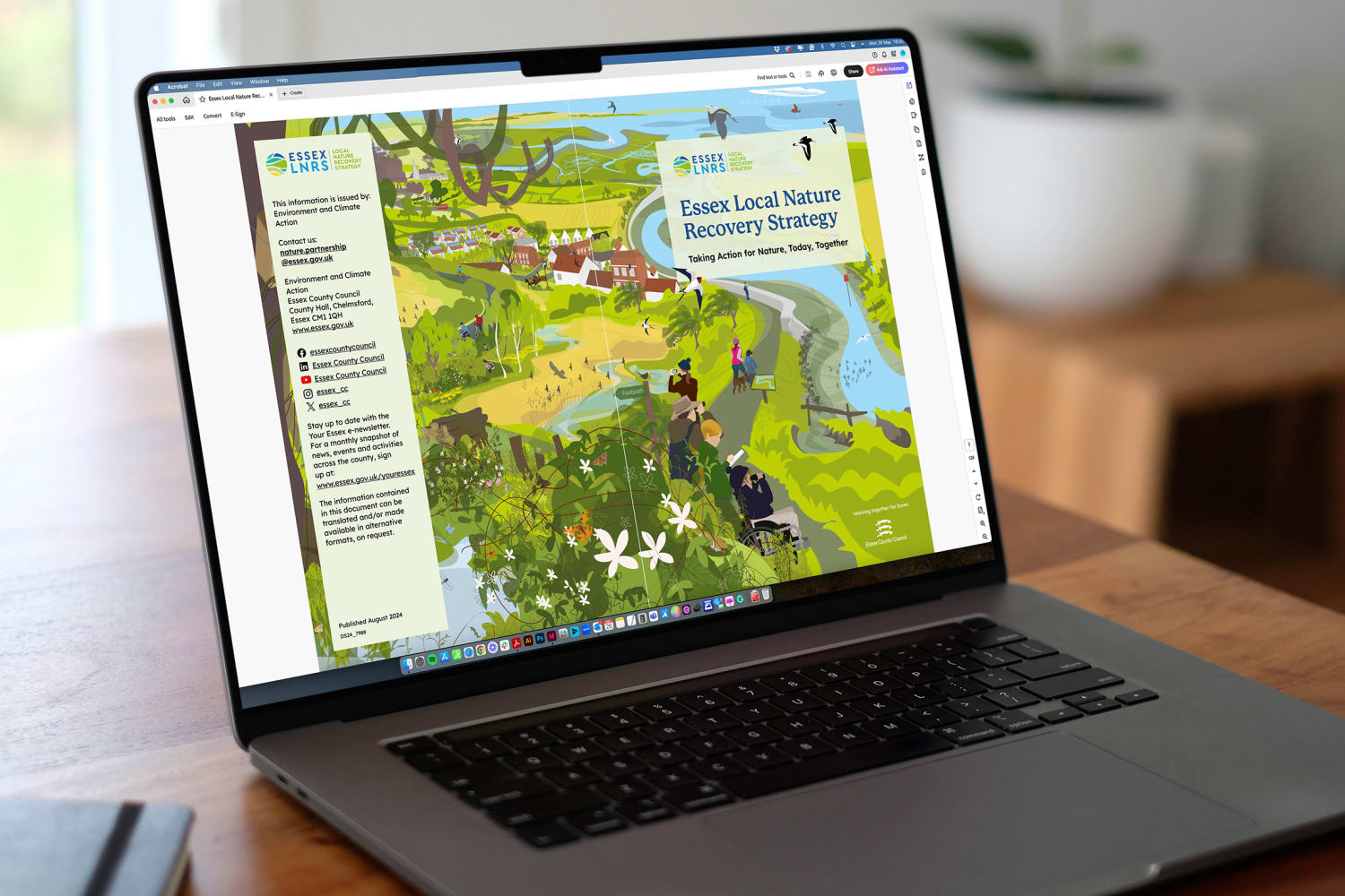 The front and back covers of the Essex Local Nature Recovery Strategy PDF are displayed on an open MacBook, on a wooden desk.