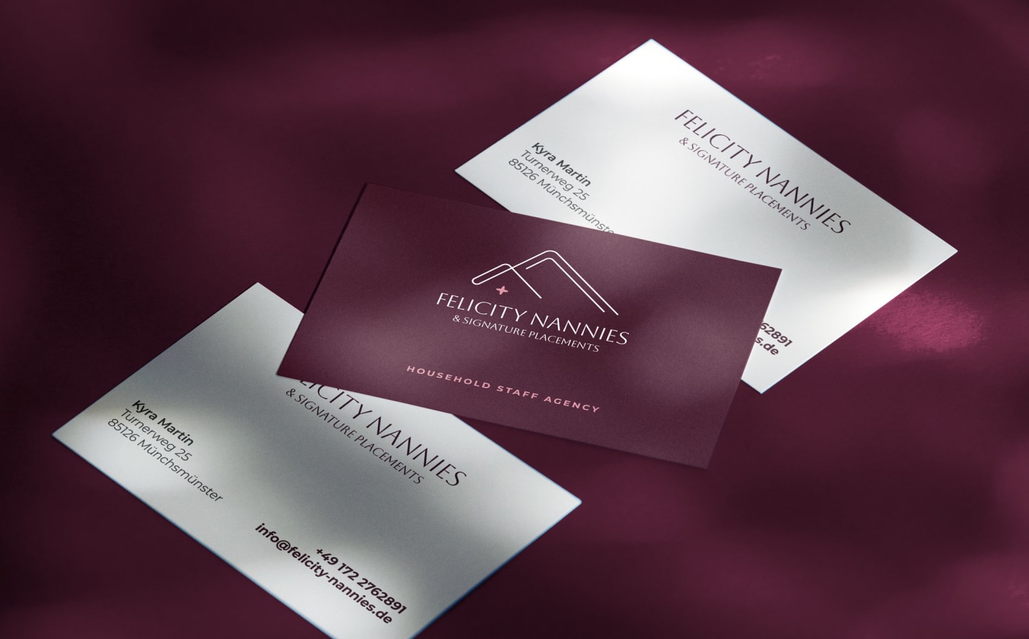 Business cards for Felicity Nannies showing both sides of the cards, on a purple cloth background.