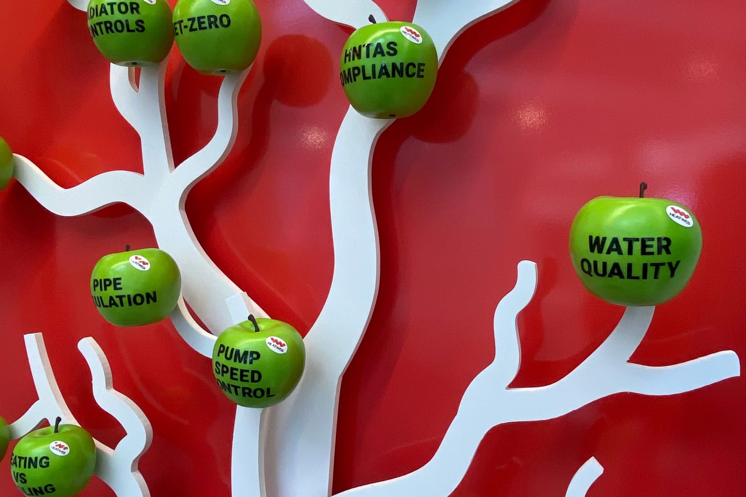 Photo of part of a stand showing a stylised tree with a white trunk and branches with various apples in place. Each apple has some text printed on it referencing an aspect of the importance of net zero.