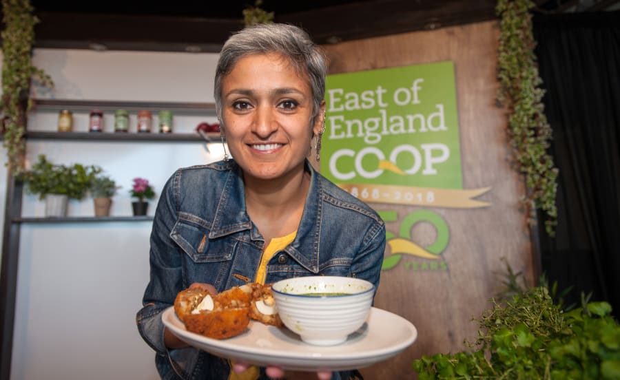 Chetna Makan, a contestant from The Great British Bake Off, proudly presents a plate of food to the camera.