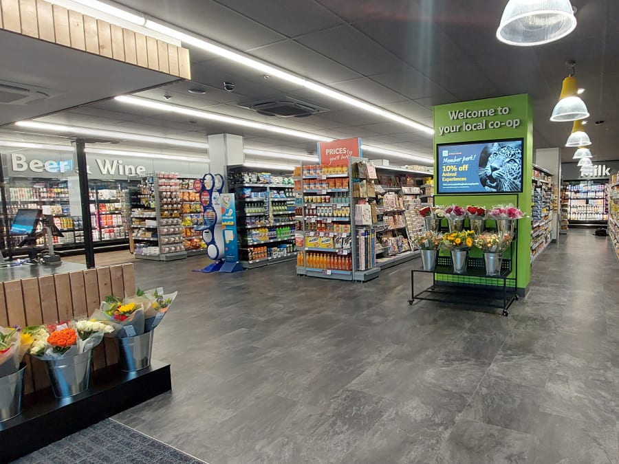 Needham Market food store interior showing bulkhead category messaging for Beer & Wine, and Milk.