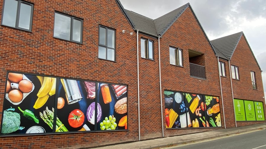 Needham Market food store window vinyls in place, showing stock imagery of various cutout food items on a dark blue background
