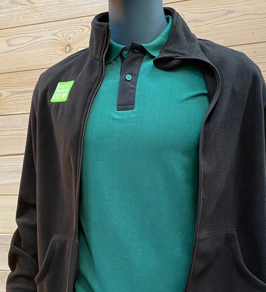 Sample uniform pieces: a dark green long-sleeved polo shirt under a black fleece with the company logo embroidered on it.