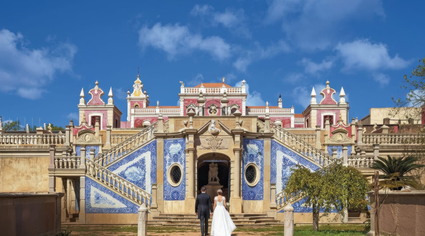 Jardins do palácio rococó de Estói com caminhos em terraço, azulejos clássicos azuis e brancos e paredes rosa do palácio.