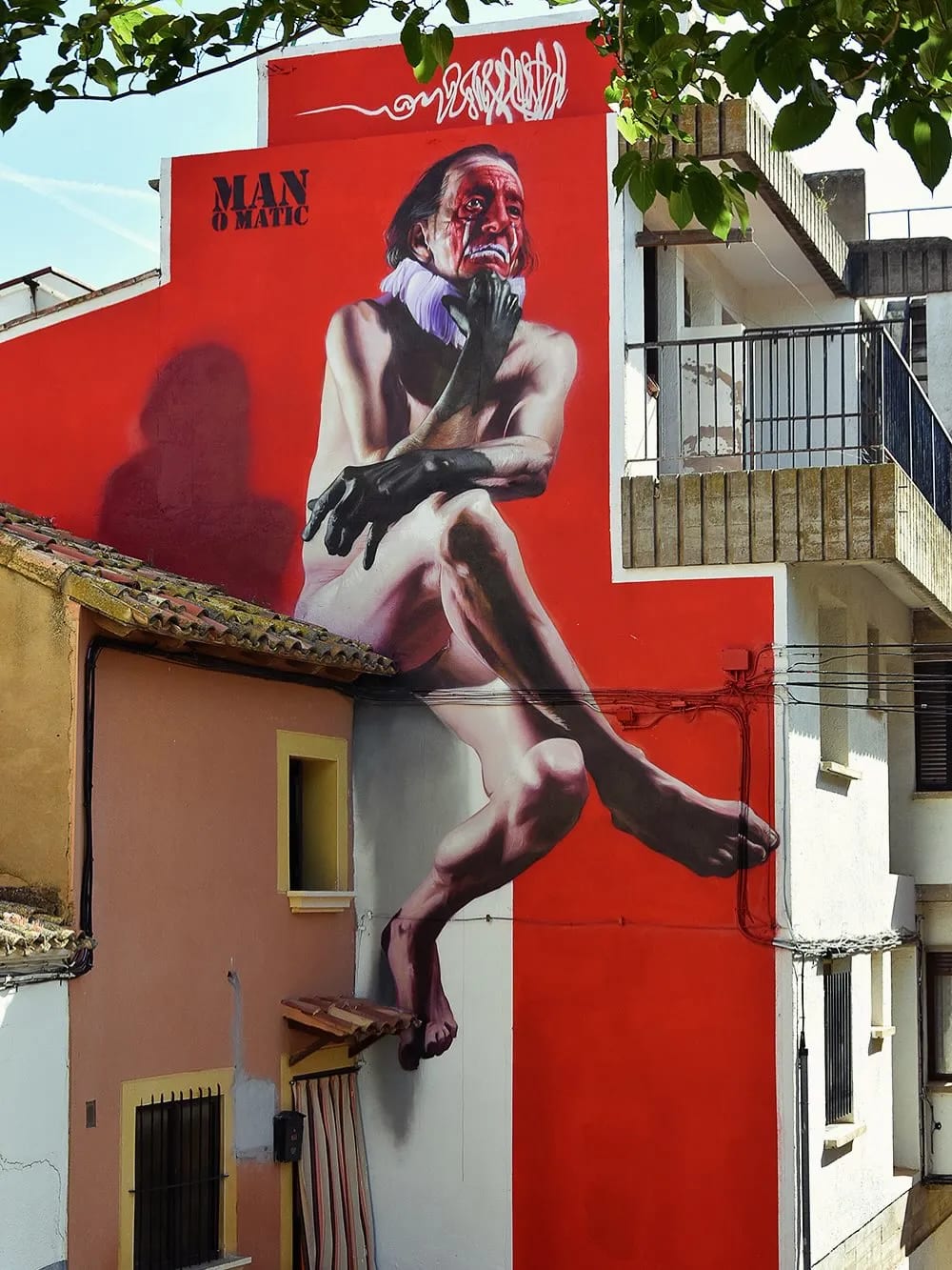 Mural de un hombre sentado con guantes negros en una pared roja.