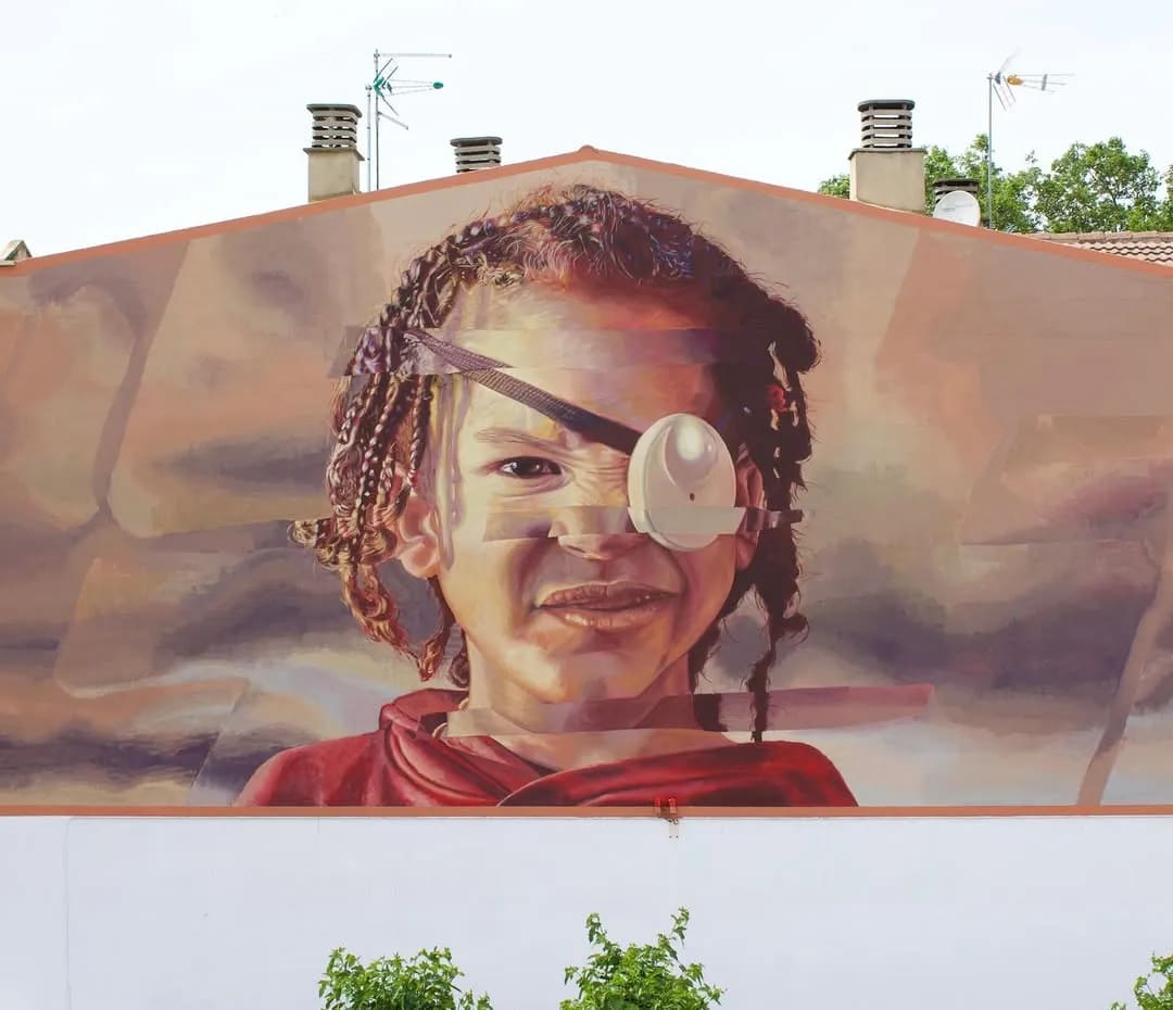 Mural de un niño con trenzas y un parche en el ojo en una pared.