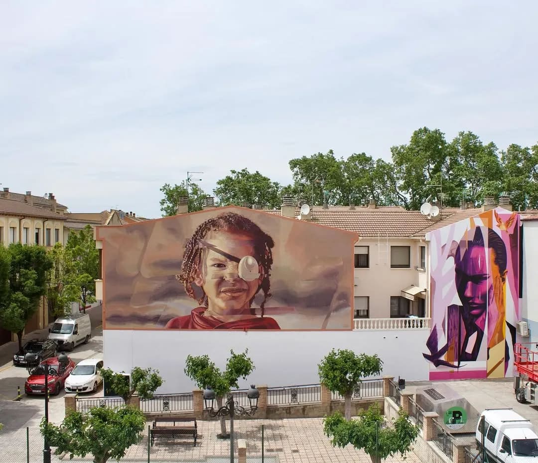 Mural de un niño con parche en el ojo en un edificio urbano.