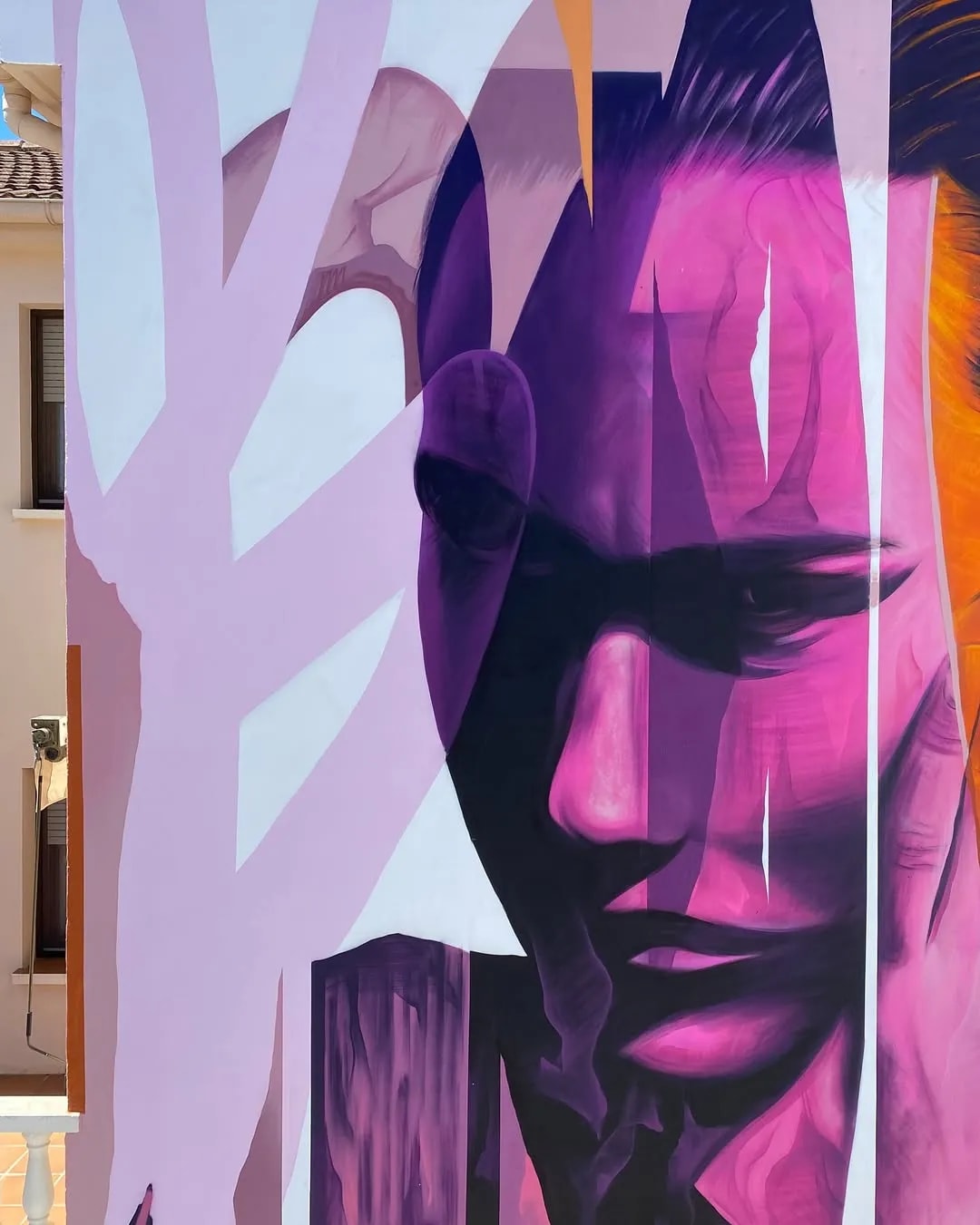 Mural de una cara con tonos morados y rosados.