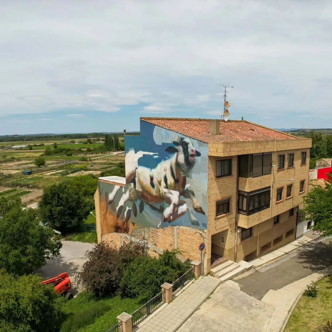 Edificio con mural de una cabra corriendo en una zona rural.