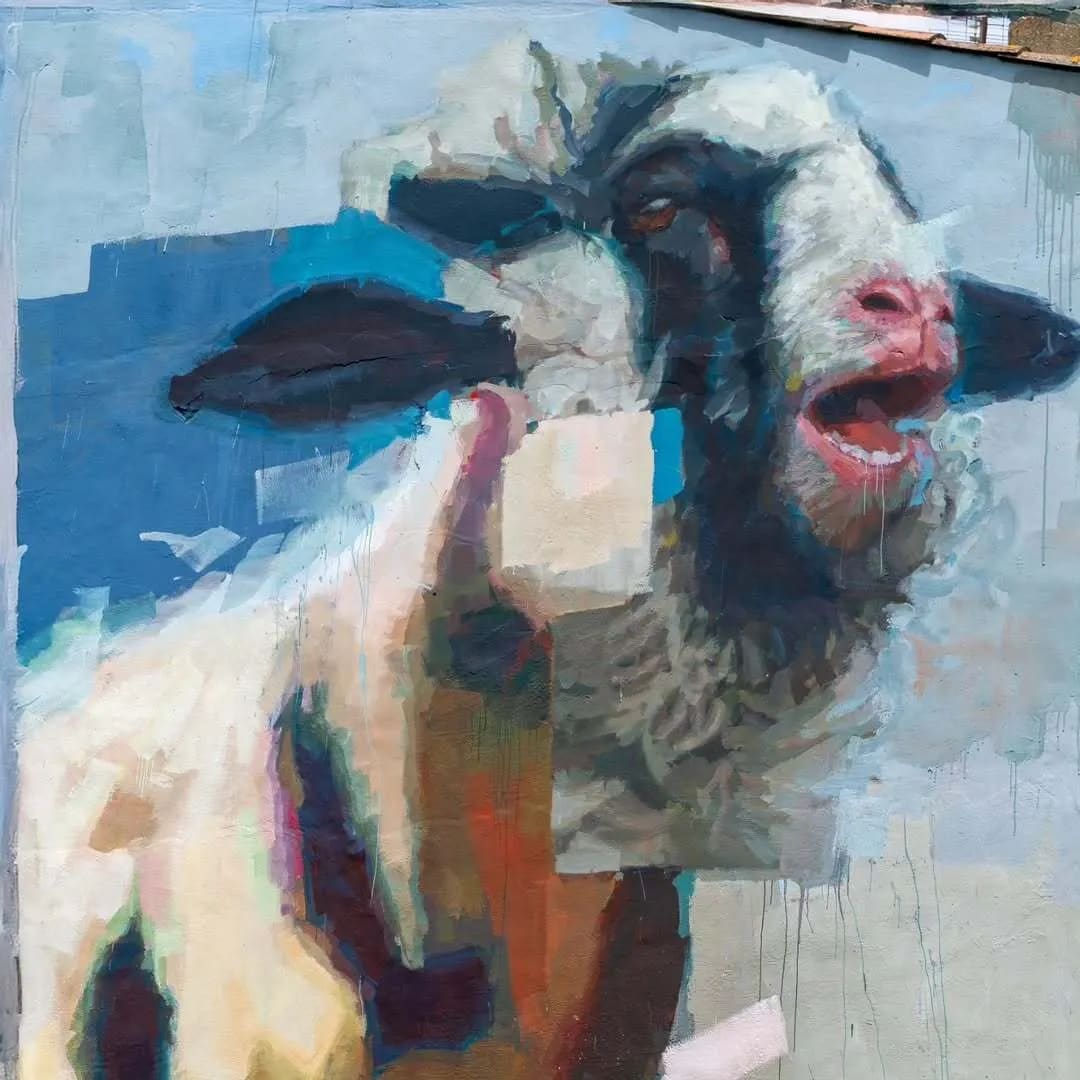 Cabra con la boca abierta sobre fondo azul.