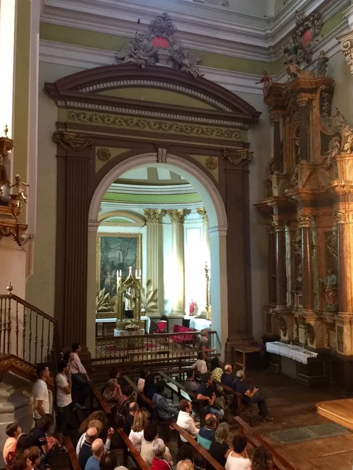 Interior de iglesia con asientos de madera y ornamentos dorados.