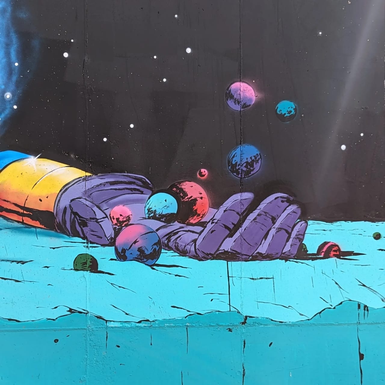 Mano gigante en el espacio con bolas de colores flotando.