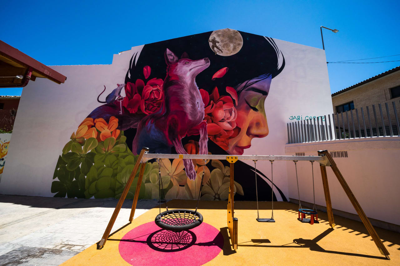 Mural de una mujer con flores y un zorro, con un columpio delante.