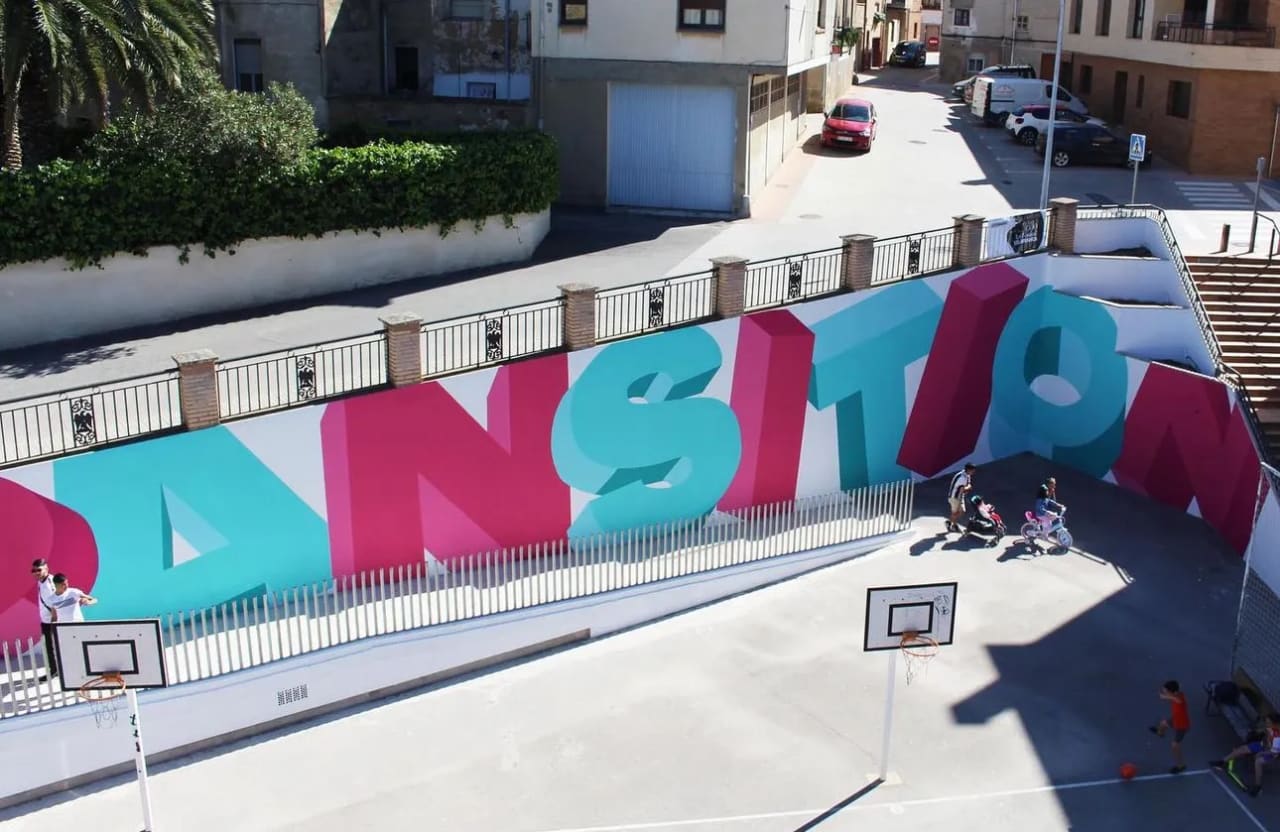 Cancha de baloncesto con grafitis en una azotea, niños jugando y personas alrededor.