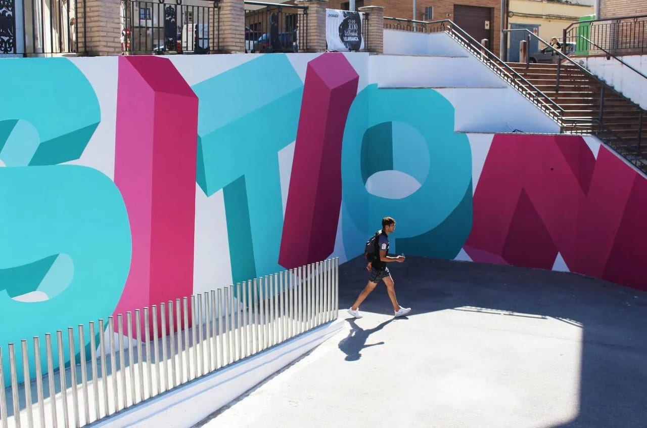 Hombre caminando junto a una pared con grafitis coloridos.