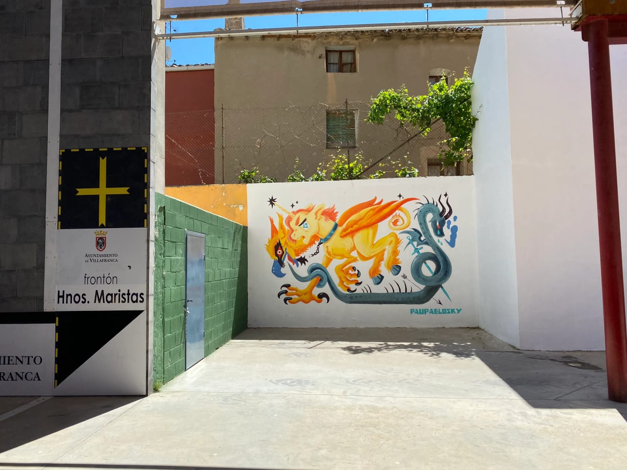 Mural de un dragón o quimera con colores brillantes en una pared blanca.