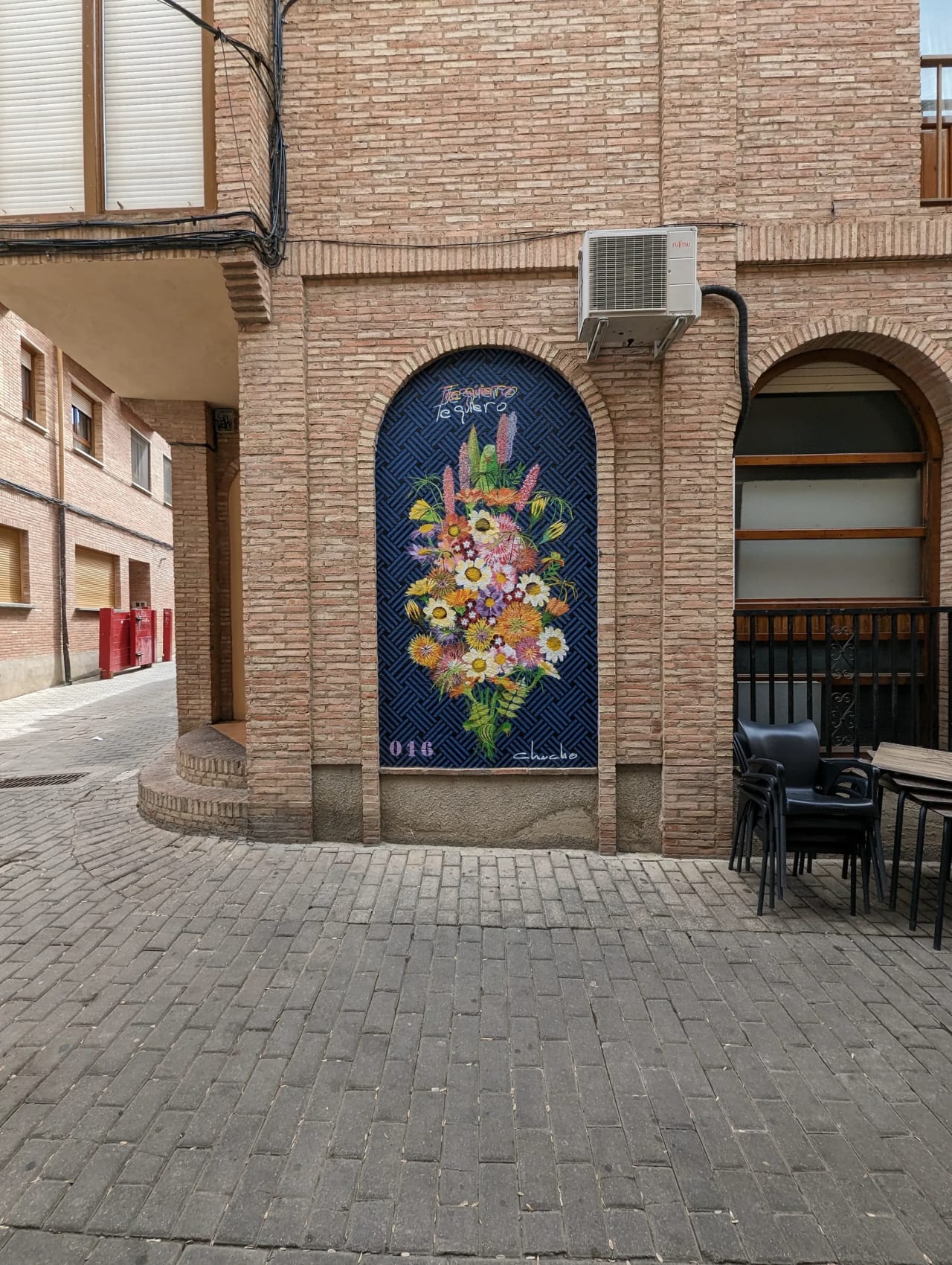 Mural de flores en una pared de ladrillos con la frase "Te quiero te quiero".
