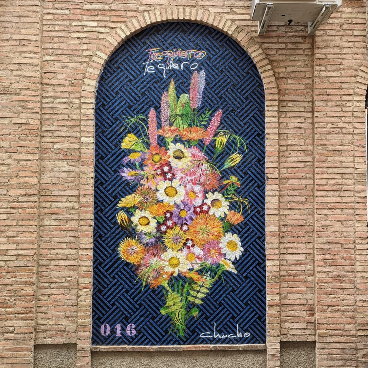 Mural de flores en arco con texto que dice "Te cuidas, te quiero".