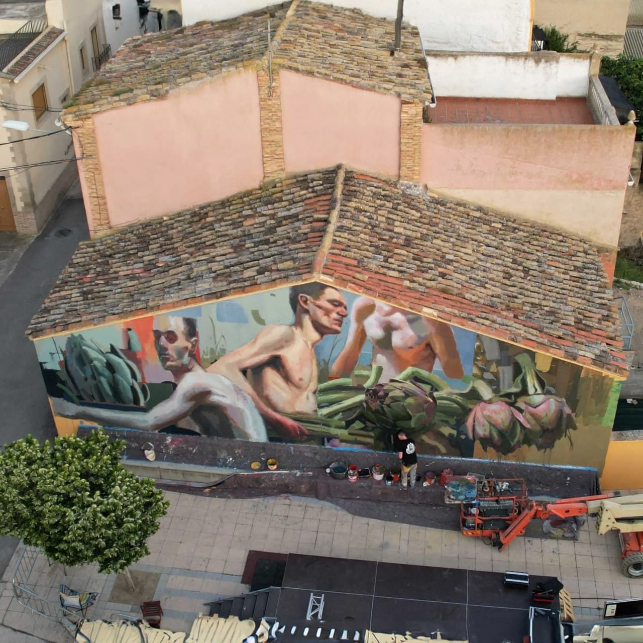 Mural de hombres desnudos y alcachofas en una pared de un edificio.