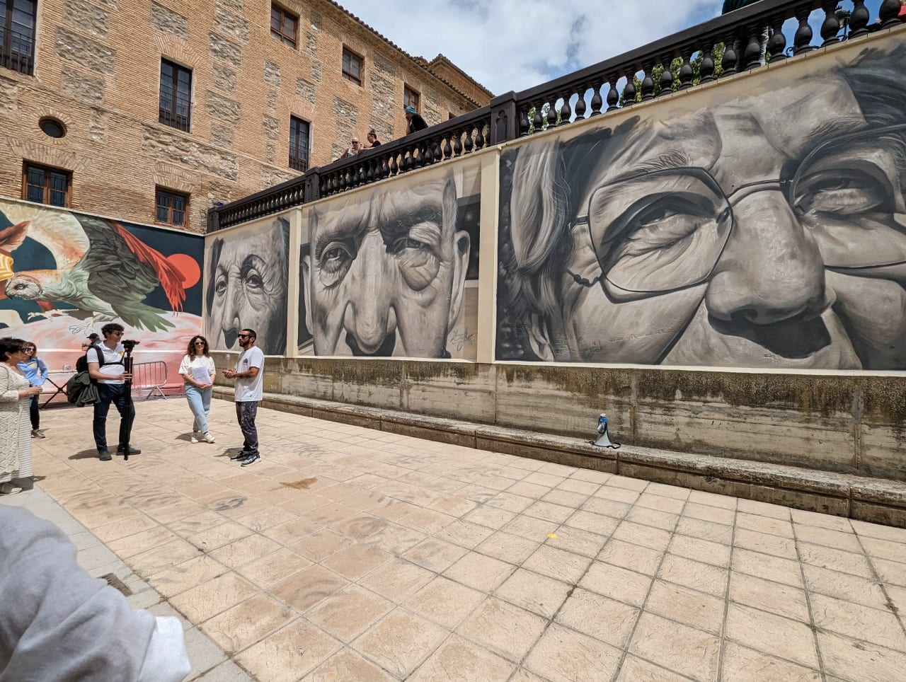 Mural de retratos realistas de ancianos en una pared exterior.