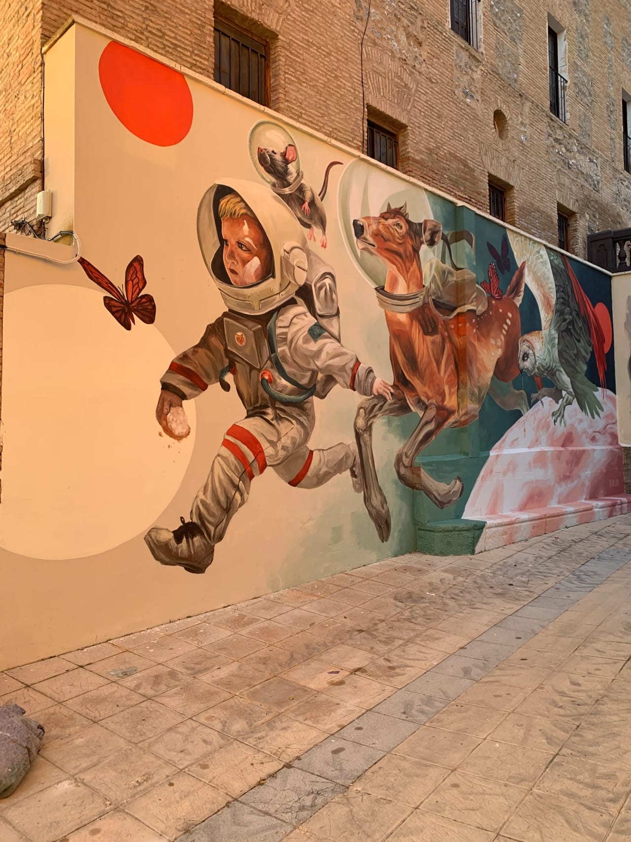 Astronauta flotante con perro y animales en mural colorido.