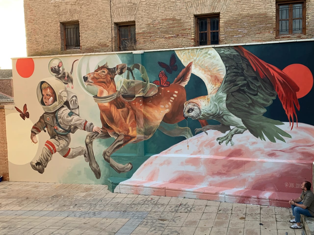 Mural de un niño astronauta y varios animales volando hacia un planeta.