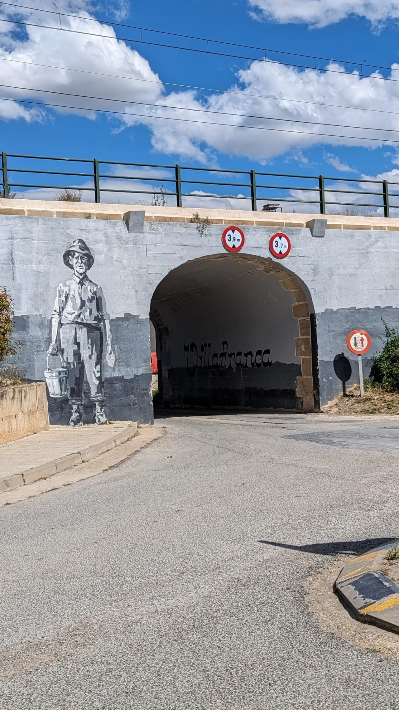 Túnel con mural de un hombre y señales de tráfico bajo un puente.