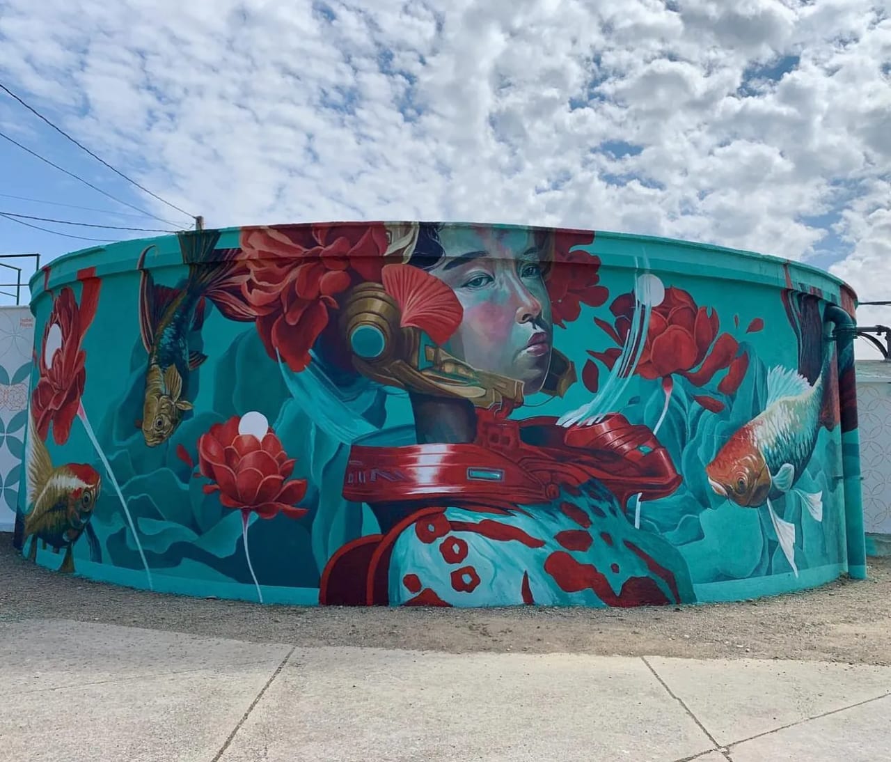 Mural en un tanque de agua con una mujer y peces de colores.
