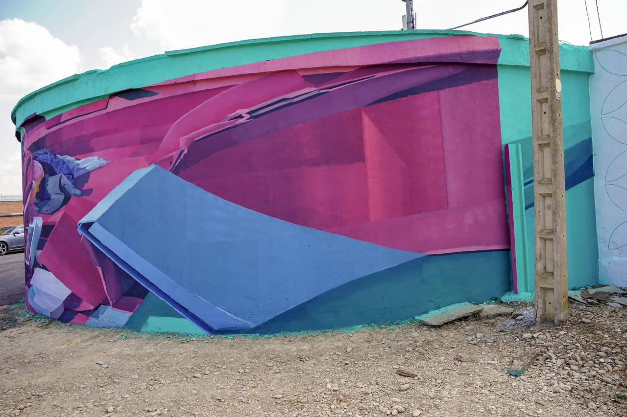 Mural en tonos rosados, azules y verdes en una pared curva.