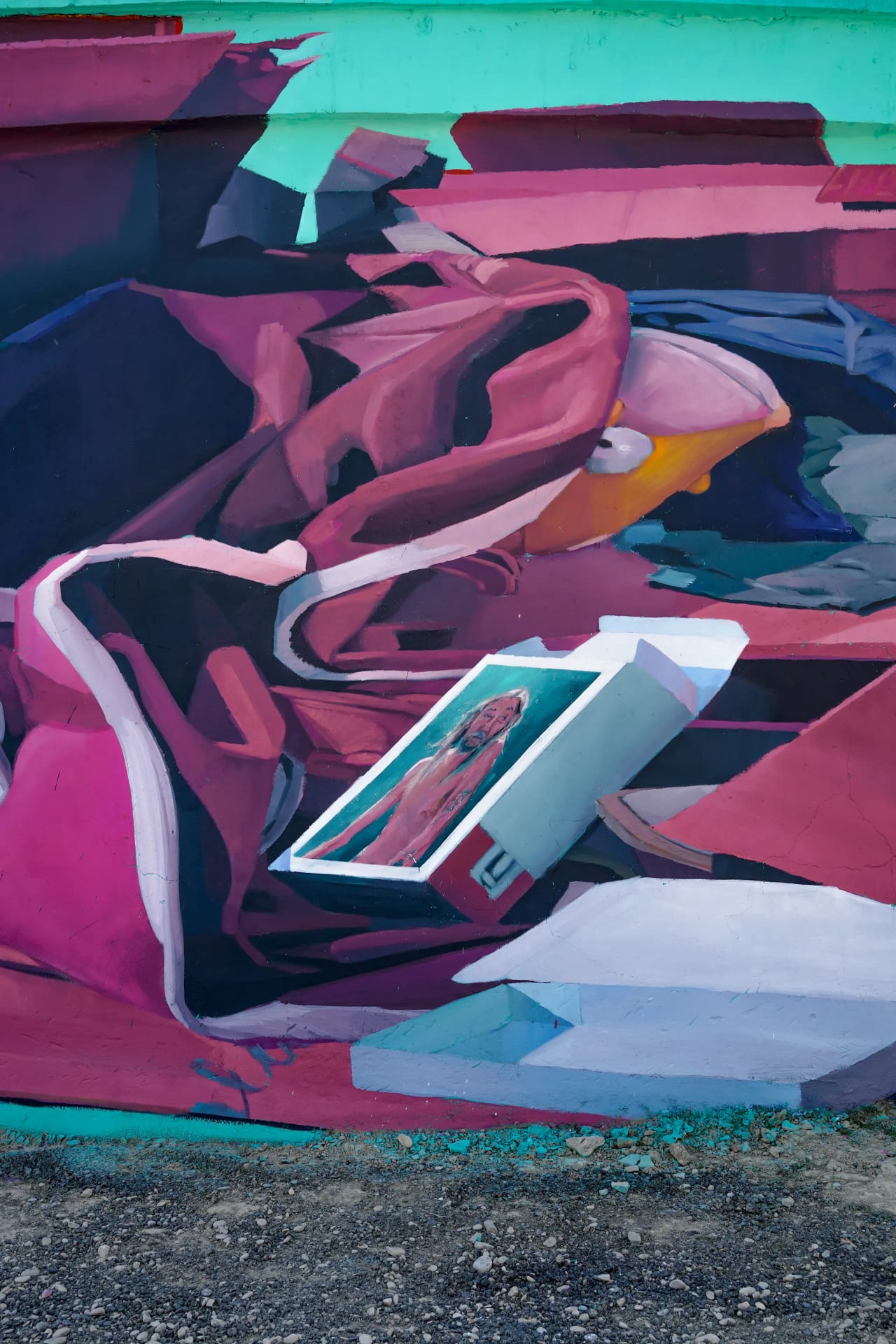 Mural con colores vibrantes de rosa, azul y verde con una obra de arte enmarcada.