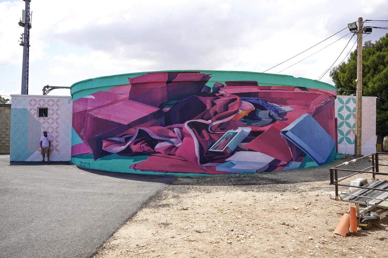 Mural de colores en una pared curva con ropa y libro en el centro.