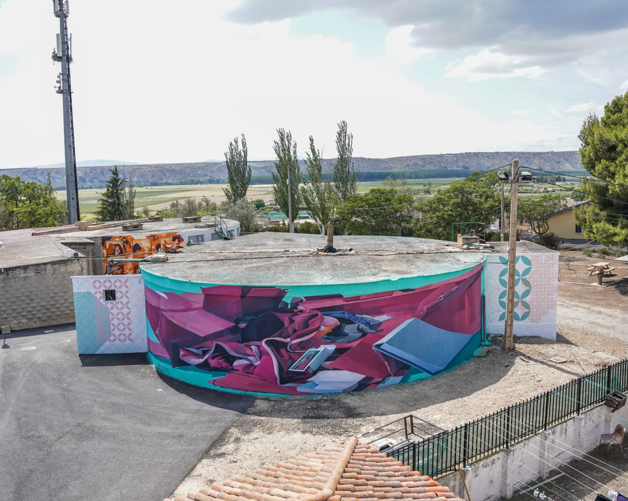 Mural colorido en un edificio circular en un entorno rural.